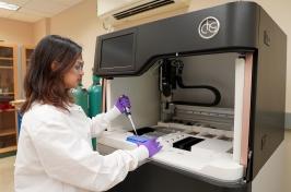 A young woman uses a syringe to add material to a tray with DNA samples